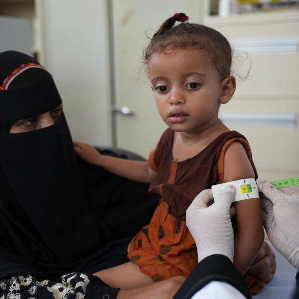 Radhya, young girl in Yemen, has her arm measured with a strip of tape by a doctor in a UNICEF-implemented nutrition service.