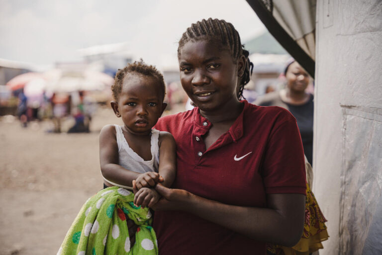 In a UNICEF-supported vaccine centre, a mum holds her 11-month-old child.