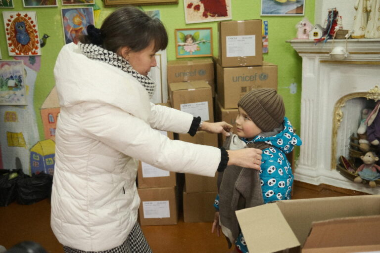 A 7 year old tries on a jacket and a hat from the UNICEF winter set of children's warm clothes.