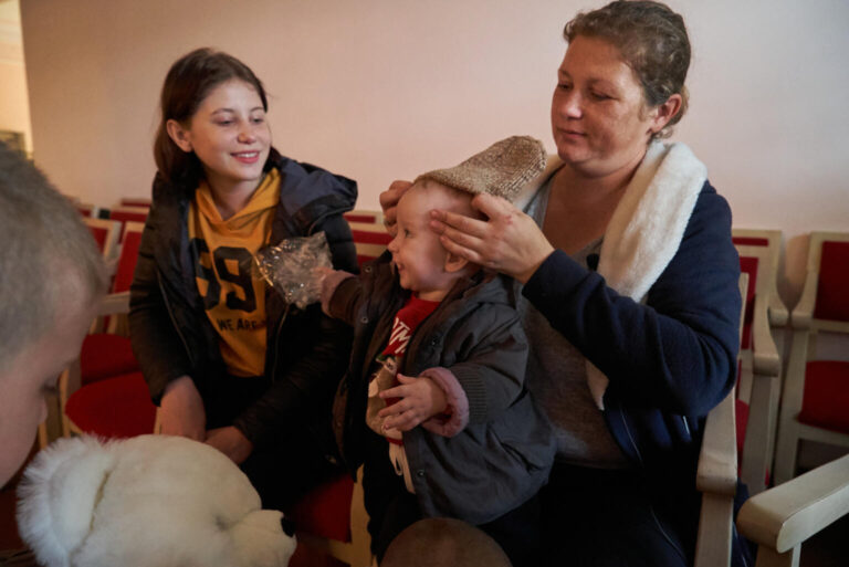 A mother puts a warm hat on her 10-month-old child.