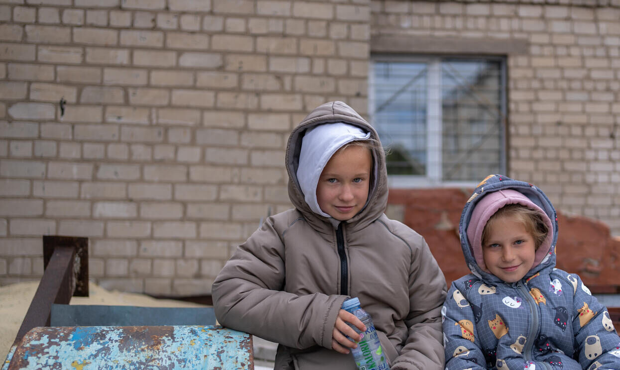 Two sisters are sitting together outside.